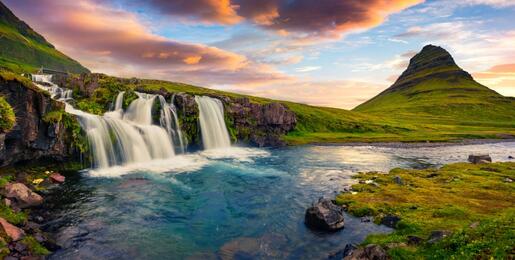 Summer sunset on famous Kirkjufellsfoss Waterfall and Kirkjufell mountain. Colorful evening panorama.